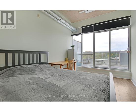 A bedroom with a large bed and a view of the outside through the windows.