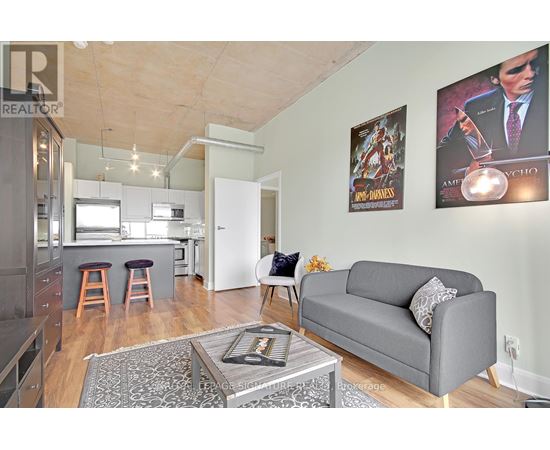 A living room with a grey couch and a coffee table in front of a wall with posters.