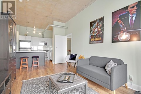 A living room with a grey couch and a coffee table in front of a wall with posters.