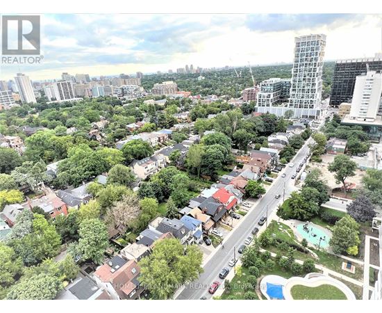 A bird's eye view of a residential area with a swimming pool and a tall building in the distance.