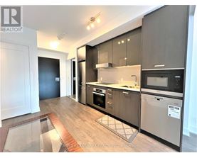 A modern kitchen with dark wood cabinets and stainless steel appliances.