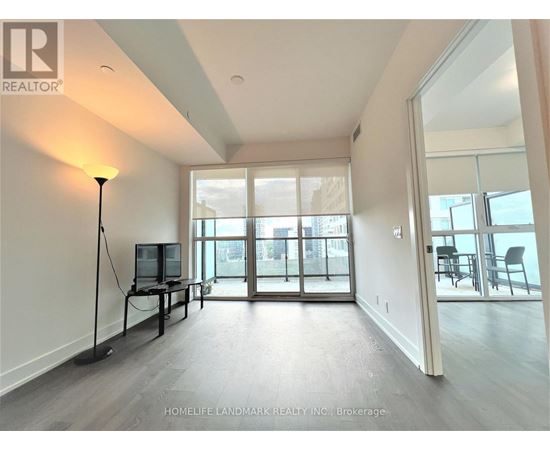 A well-lit, spacious living room with a television and sliding glass doors.