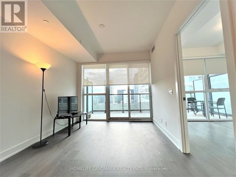 A well-lit, spacious living room with a television and sliding glass doors.