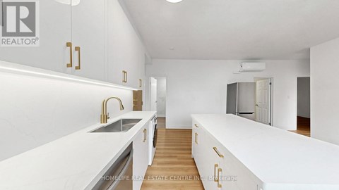 A modern kitchen with white cabinets and a wooden floor.