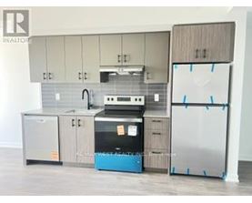 A kitchen with a refrigerator, sink, and cabinets is being photographed for a realtor.