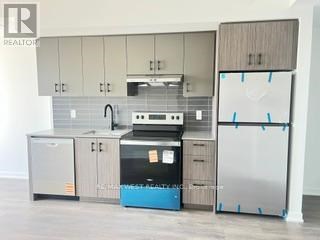 A kitchen with a refrigerator, sink, and cabinets is being photographed for a realtor.