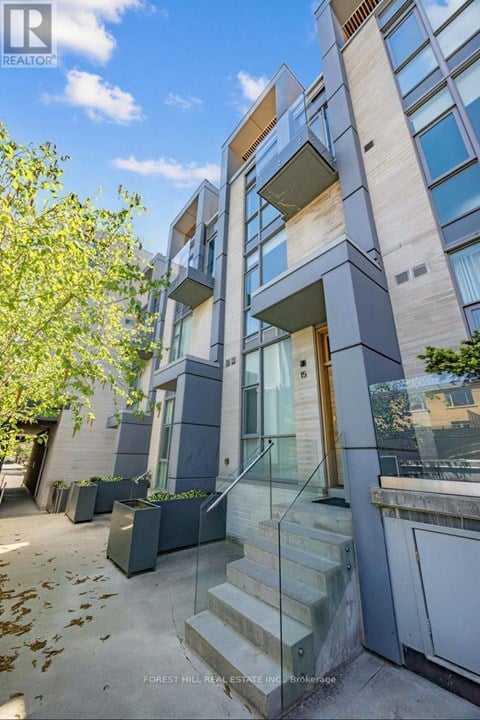 A modern building with a glass entrance and a tree in front.