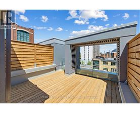 A wooden deck with a glass railing and a view of the city.