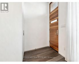A white hallway with a wooden door and a Forest Hill Real Estate Inc. logo.