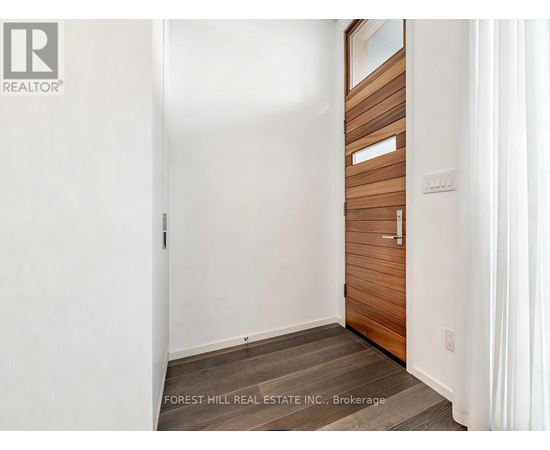 A white hallway with a wooden door and a Forest Hill Real Estate Inc. logo.