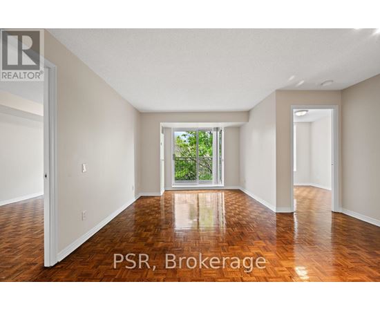 A room with wooden floors and a large window with a view of trees outside.