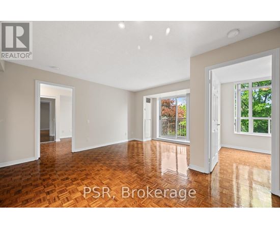 A room with wooden flooring and white walls, with a window showing greenery outside.
