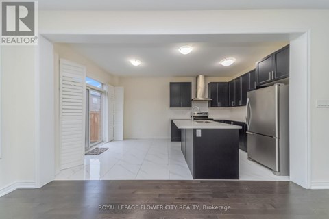 A kitchen with black cabinets and a stainless steel refrigerator.