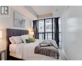 A bedroom with a large bed and a window with black curtains.