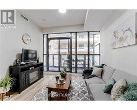 A living room with a grey couch, a wooden coffee table, a flat screen TV, and a glass door leading to a balcony.