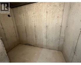 A dirty, unfinished basement with concrete walls and floor.