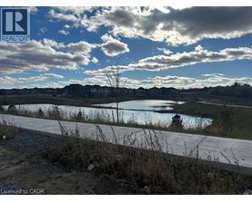 A realtor's photo of a landscape with a body of water and houses in the distance.