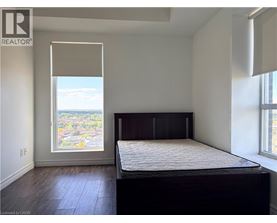 A bedroom with a large bed and a window overlooking a cityscape.