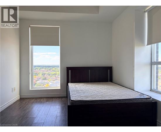 A bedroom with a large bed and a window overlooking a cityscape.