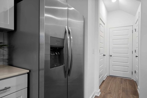 A stainless steel refrigerator in a kitchen with white cabinets.