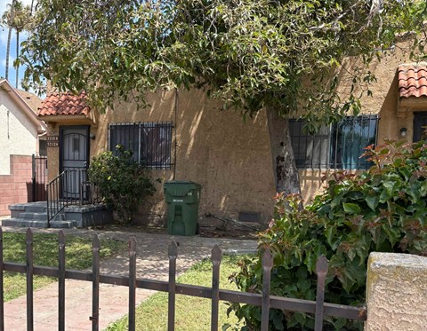 A house with a green trash bin in front of it.