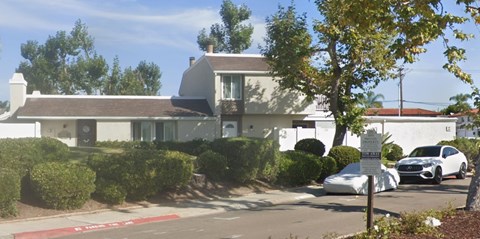 A white house with a black car parked in front.