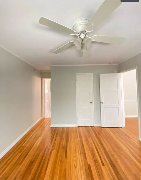 A room with a ceiling fan and wooden floors.