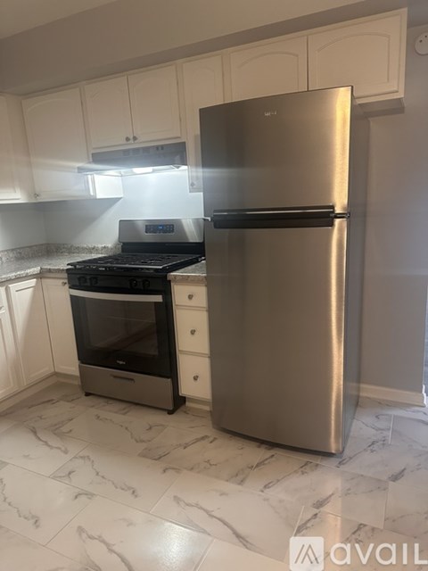 A kitchen with a stainless steel refrigerator and a black stove top oven.