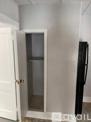 A white door is open to a small, empty room.