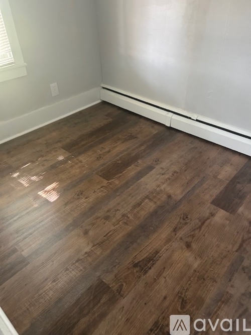 A room with wooden flooring and white walls.