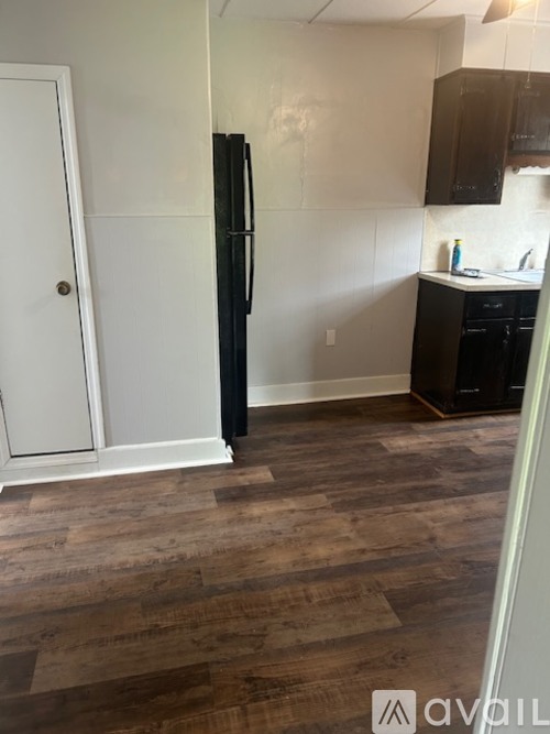 A kitchen with a black fridge and wooden floors.