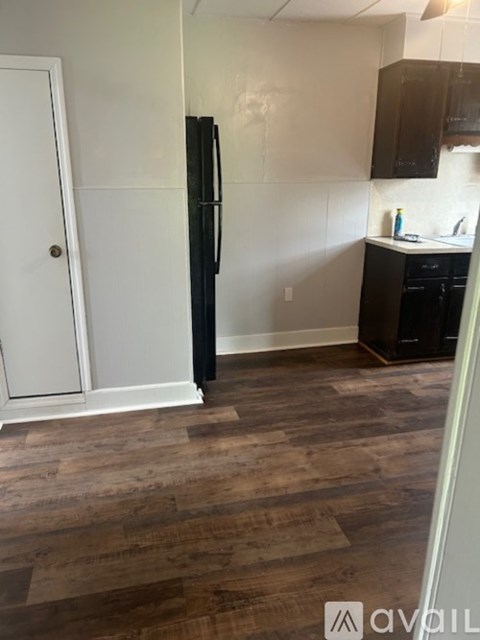 A kitchen with a black fridge and wooden floors.