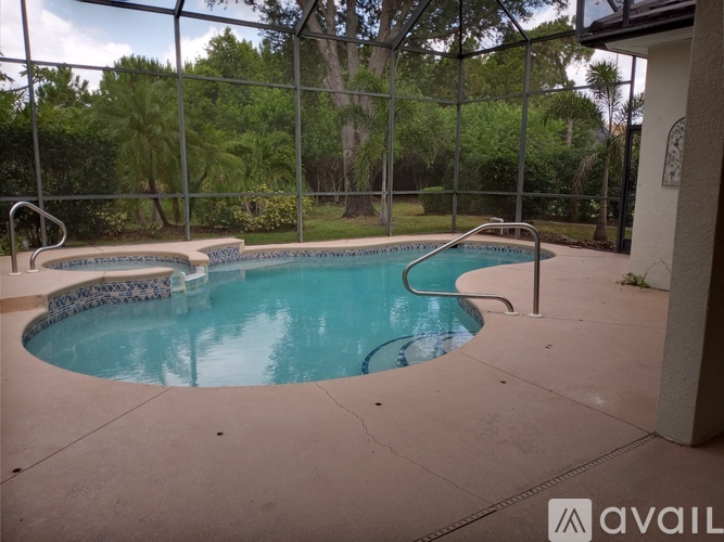 A pool surrounded by a fence with trees in the background.