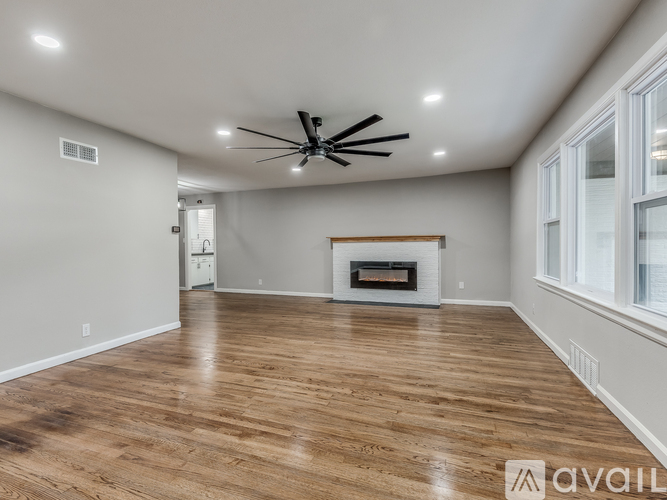 A spacious room with a fireplace and wood flooring.