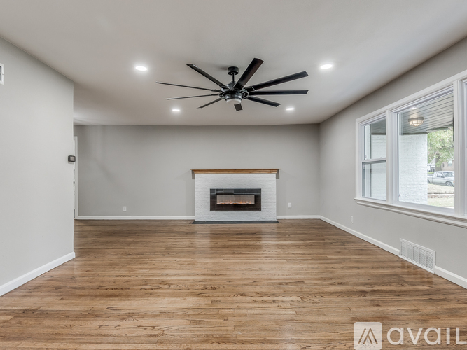 A spacious room with a fireplace and a ceiling fan.
