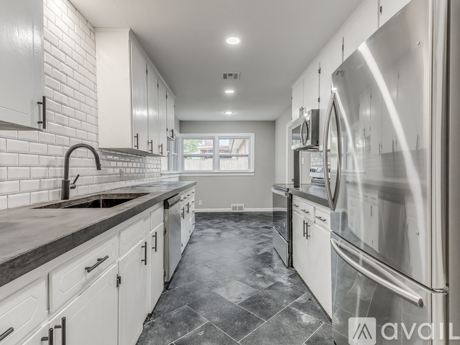 A modern kitchen with white cabinets and stainless steel appliances.