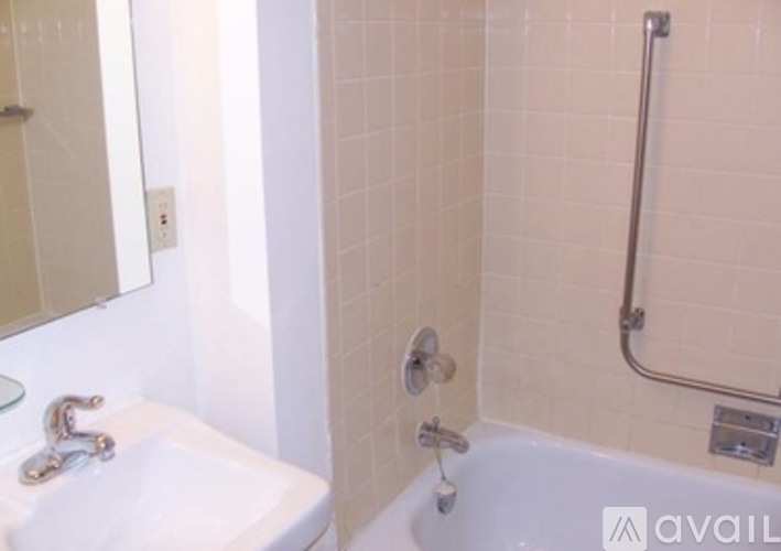 A white sink with a silver faucet is in a bathroom with a white tub and a shower head.
