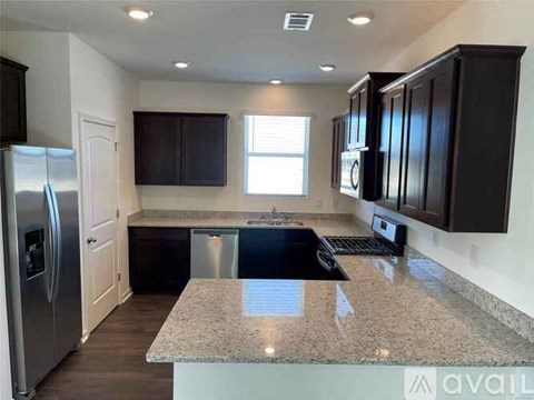 A kitchen with dark brown cabinets and a granite countertop.