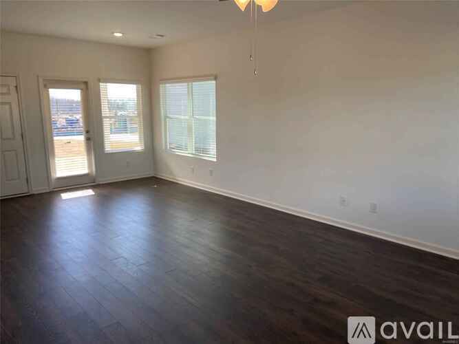A spacious room with wooden floors and two windows.