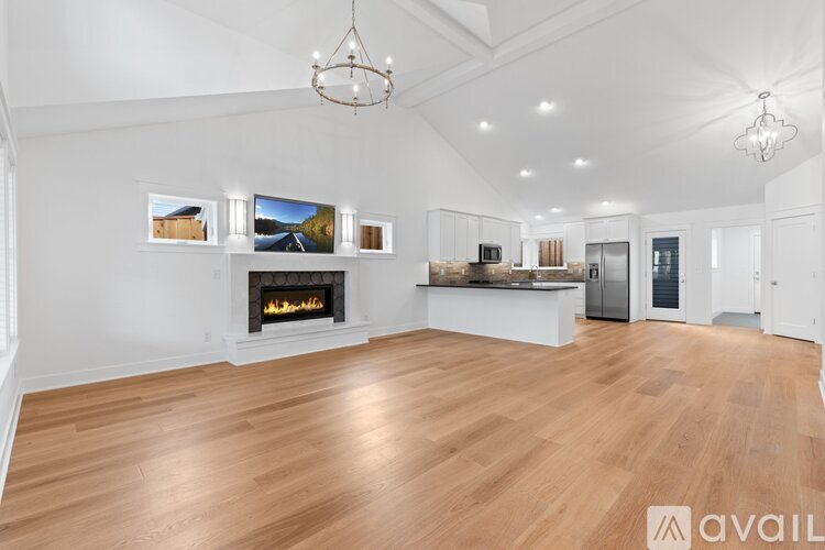 A spacious living room with a fireplace and a chandelier.