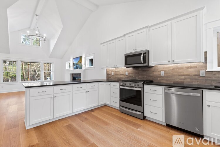 A kitchen with white cabinets and a black microwave above the stove.