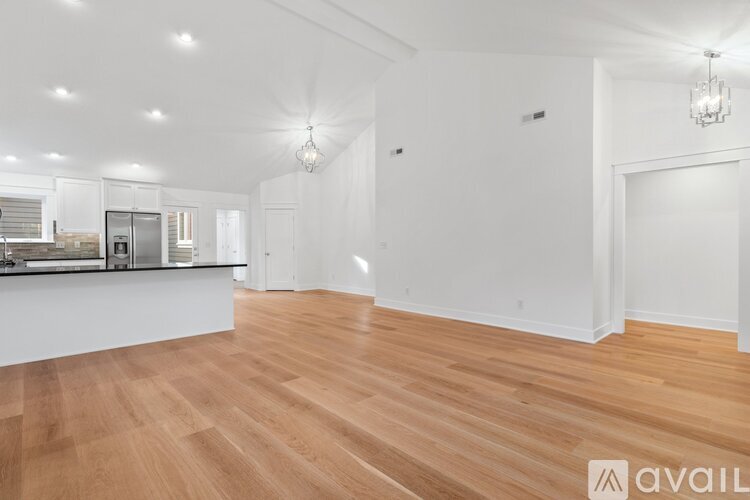 A spacious room with wooden flooring and white walls.
