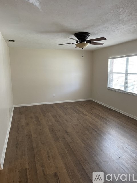 A room with a ceiling fan and wooden flooring.