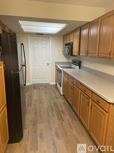 A kitchen with wooden cabinets and a black fridge.