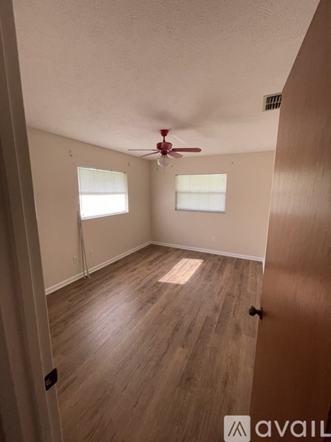 A room with a ceiling fan and two windows.