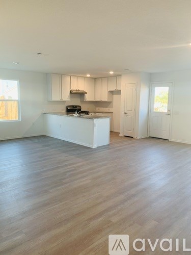 A spacious kitchen with white cabinets and a wooden floor.