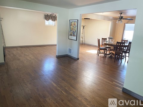 A room with wooden floors and a dining table set up.
