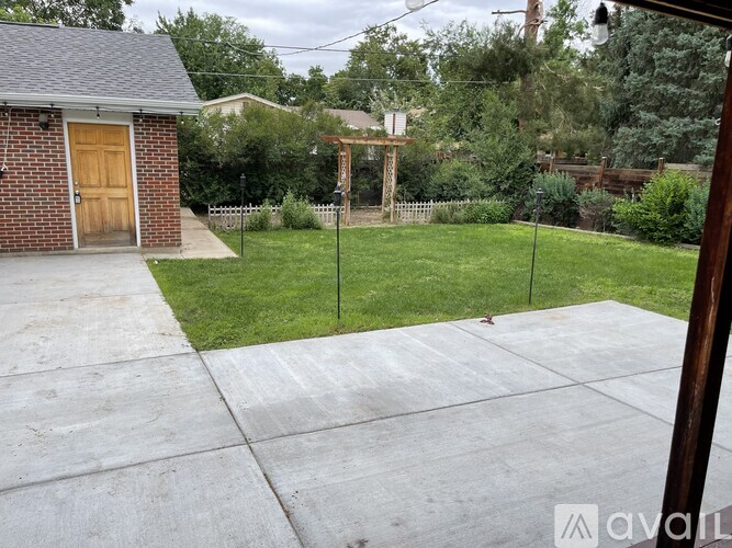 A backyard with a concrete patio and a small building.
