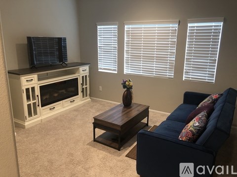 A living room with a blue couch, a wooden coffee table, and a television.