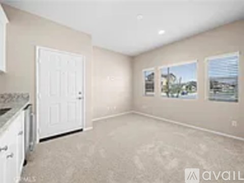A room with a white door and a window showing a view of a building.